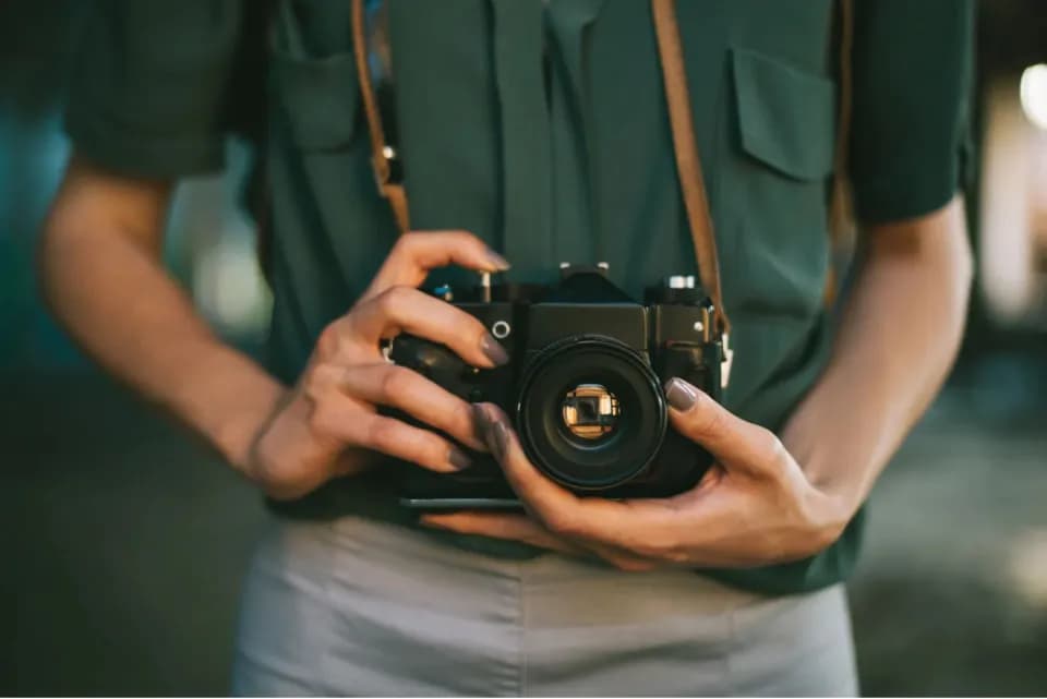 A person in a green shirt holding a film camera with both hands